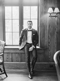 a man in a suit and bow tie sitting on a window sill