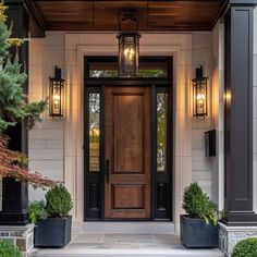 the front door of a house with two planters on either side and one light hanging above it