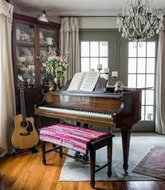 a grand piano in a living room with a chandelier