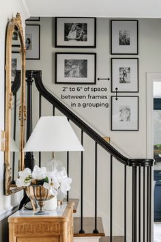 a staircase with pictures on the wall above it and a lamp next to an end table