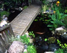 a wooden bridge over a small pond in a garden