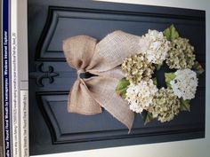 the front door is decorated with a burluck wreath and hydrangea flowers