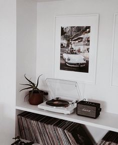 a record player sitting on top of a white shelf next to a potted plant