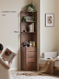 a woman sitting on a couch reading a book in front of a bookshelf