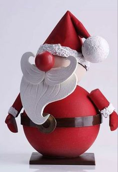 a santa clause figurine sitting on top of a red ball with white trim