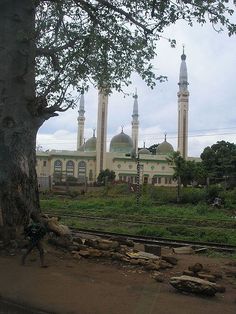 a large white building sitting next to a lush green field with trees in front of it