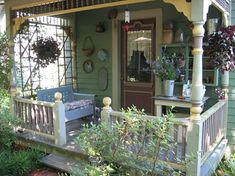 a blue couch sitting on top of a wooden porch next to flowers and plants in front of a green house