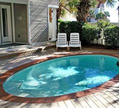 a small swimming pool in the middle of a backyard with two lawn chairs on it