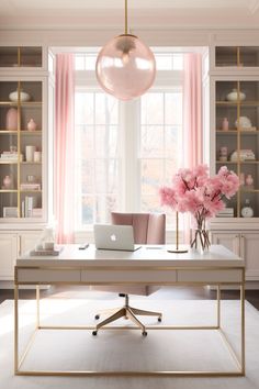 a desk with a laptop on it and pink flowers in vases next to the window