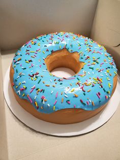 a blue frosted donut with sprinkles sits on a white plate