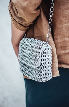 a woman is holding a silver purse