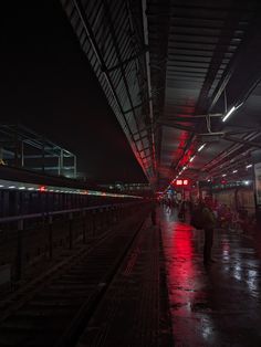 people are waiting at the train station in the rain