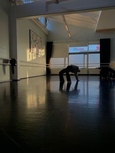 a man is doing a handstand on the floor in an empty room with large windows