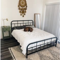 a dog laying on top of a white bed in a room with wood flooring