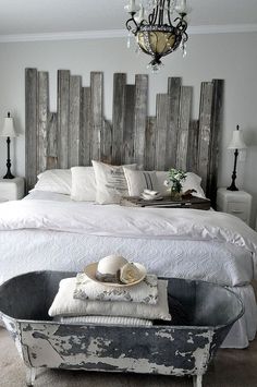 a bedroom with a bed, chandelier and an old tub in the middle