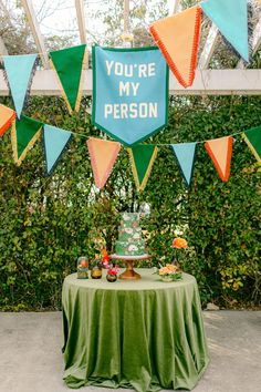 a table topped with a cake covered in frosting and flags that say you're my person