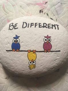 a rock with two owls on it that says be different