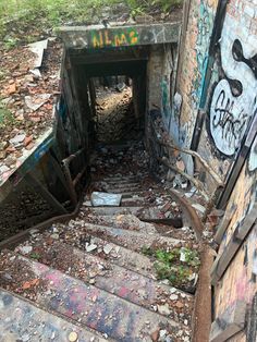 an abandoned stairway with graffiti on the walls and steps leading up to another set of stairs