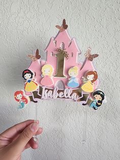 someone is holding up a cake topper with princesses on it and the number one