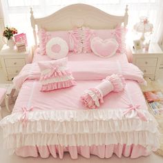 a pink bed with ruffles and pillows on it