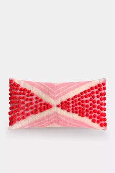 a pink and white pillow with red beads on it