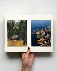 a hand holding an open book with two paintings on it