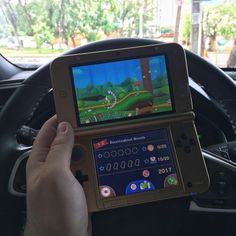 a person is holding up a game on their tablet in the driver's seat