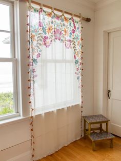 a room with a window and a small table in front of the window that has flowers on it