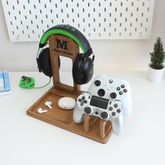 two video game controllers sitting on top of a wooden stand with headphones attached to it