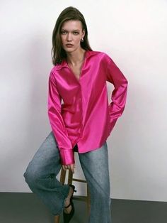 a woman is sitting on a chair wearing a pink shirt