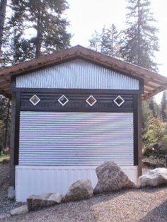 a small building sitting in the middle of a forest with rocks and trees around it