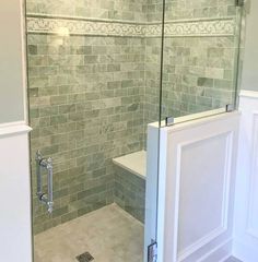 a walk in shower sitting next to a white toilet under a glass door on top of a tiled floor