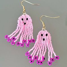 pink beaded earrings with black and white beads hanging from gold earwires on grey background