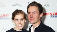 a man and woman standing next to each other in front of a white wall with the words james bluntt on it