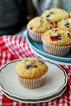 some muffins are sitting on plates on a red and white checkered tablecloth