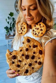 a woman holding a cookie and chocolate chip pie