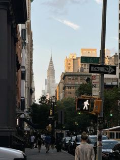 a man walking down the street in front of some tall buildings and traffic lights on a city street