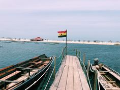 a boat docked at the end of a pier with a flag flying in the wind