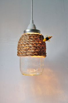 a mason jar with twine wrapped around it and a bird on top hanging from the ceiling