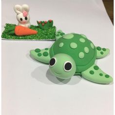 a green turtle cake sitting on top of a table next to a small bunny rabbit