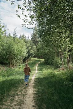 a person walking down a dirt road in the woods