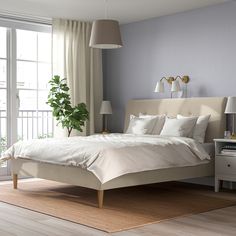 a white bed sitting next to a window in a bedroom on top of a hard wood floor