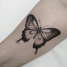 a black and white butterfly tattoo on the arm