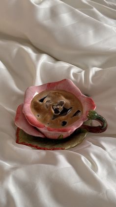 there is a coffee cup in the shape of a flower on top of a bed