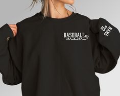 a woman wearing a black baseball sweatshirt with white writing on the sleeves and back,