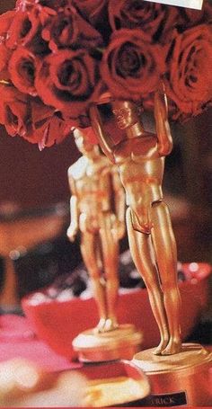 there is a gold statue with red roses in front of it and an award on the table