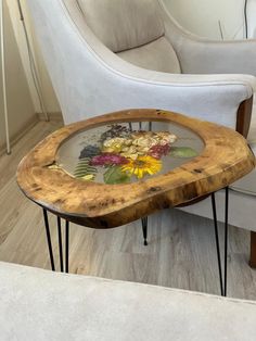 a coffee table with flowers on it and hair pins in the bottom, sitting next to a white chair