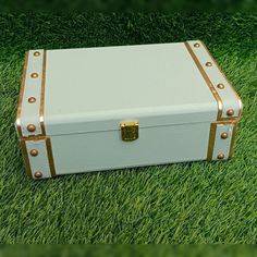 a white and gold suitcase sitting in the grass