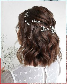 the back of a woman's head with flowers in her hair and white flowers on it