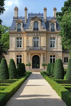 a large building with lots of hedges in front of it and trees around the entrance